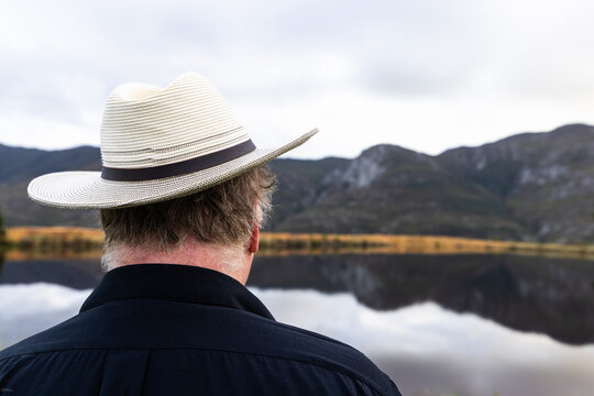 rear view of man wearing hat looking at pond