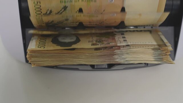 Close-up Fixed Shot of Money Counting Machine Counting 100 Crisp 50,000 Won Banknotes (Cash, Banking, Finance)