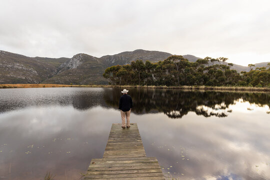 man wearing hat on wooden launch overlooking pond, Stanford, South Africa
