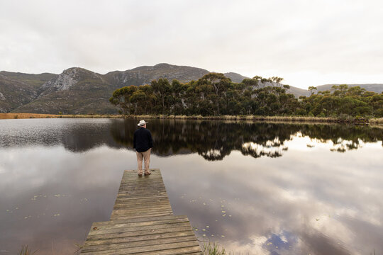 man wearing hat on wooden launch overlooking pond, Stanford, South Africa