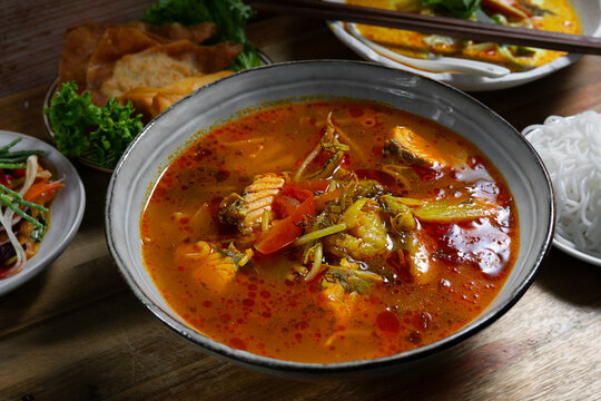 Asian fish and seafood soup served with assorted traditional Asian dishes, including vegetables, noodles, dumplings and appetizers on a restaurant table.