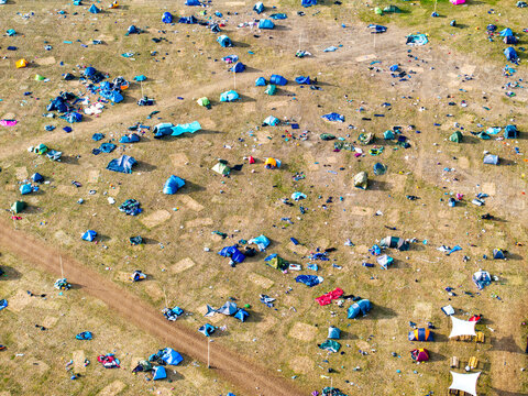 Reading, United Kingdom - 31 August 2026: Aerial view of the Reading Festival campsite featuring numerous scattered tents, discarded litter, and a dirt path across the grassy field.