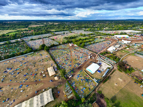 Reading, United Kingdom - 31 August 2026: Aerial view of Reading Festival campsite with numerous colorful tents, large marquees, and surrounding green fields under a dramatic cloudy sky.