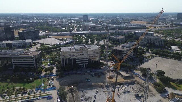 Yellow crawler cranes anchor deep foundation excavations along Internet Boulevard near Warren Parkway. Commercial building developments expand corporate sectors across Frisco, Texas