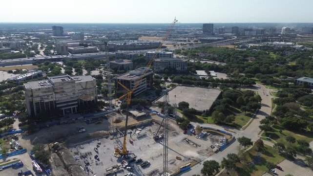Towering construction cranes overlook Hall Park office parcels bordering Dallas North Tollway. Deep earthworks expand commercial campus infrastructure along Internet Boulevard, Frisco, Texas