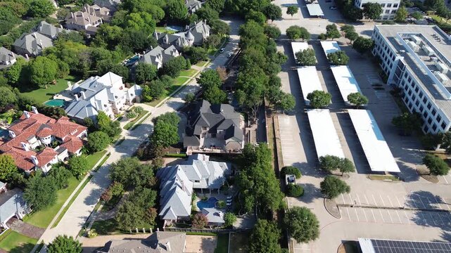 Covered vehicle stalls divide Hall Park business offices from Stonebriar Creek subdivision estates. Executive mansions border paved commercial bays along Internet Boulevard, Frisco, Texas