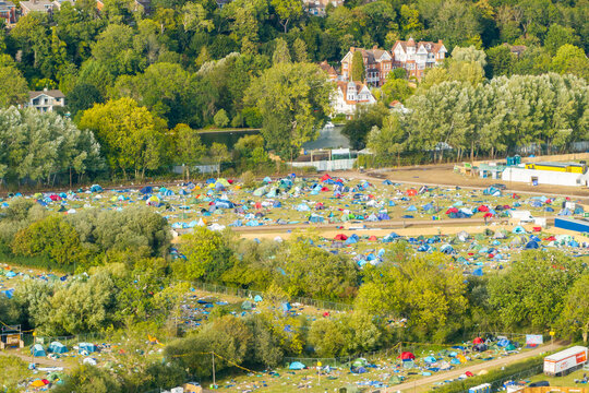 Reading, United Kingdom - 31 August 2026: Aerial view of Reading Festival campsite with numerous colorful tents on green fields, surrounded by lush trees and riverbank vegetation.