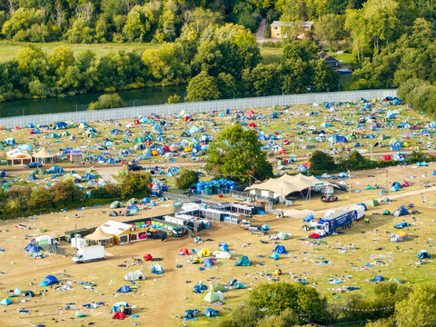 Reading, England, United Kingdom - 31 August 2026: Aerial view of Reading Festival campsite with colorful tents and event infrastructure on grassy fields near the river.