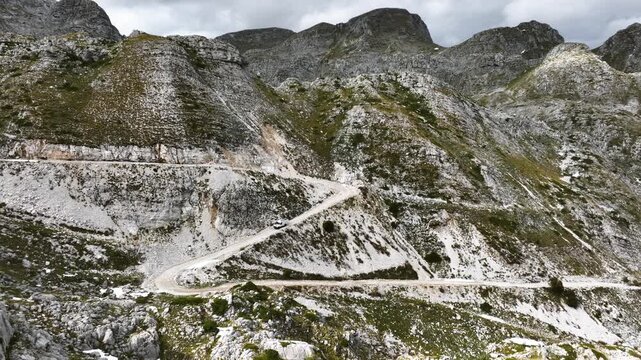 Aerial view of an off-road vehicle driving down a switchback road on a bumpy mountain trail in the south of Montenegro