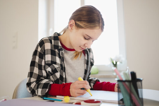 Child Using Yellow market to highlight text with marker Doing Homework in a cozy light room after school