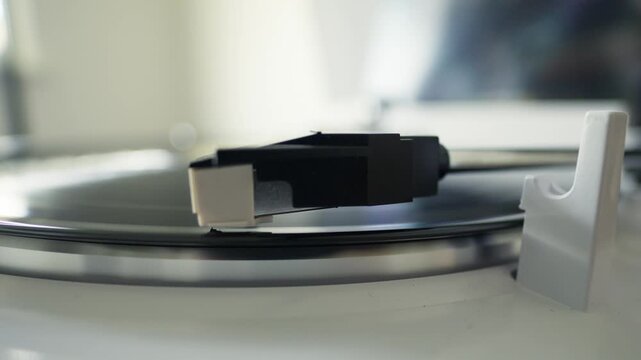 Macro shot of record player needle dropping onto spinning vinyl disc for analog music playback.