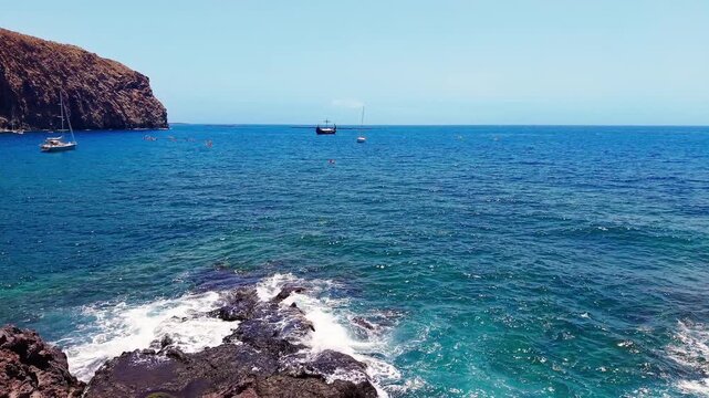 Drone flight along rugged volcanic cliffs and turquoise Atlantic waters on the wild coast near Los Cristianos in southern Tenerife, Canary Islands