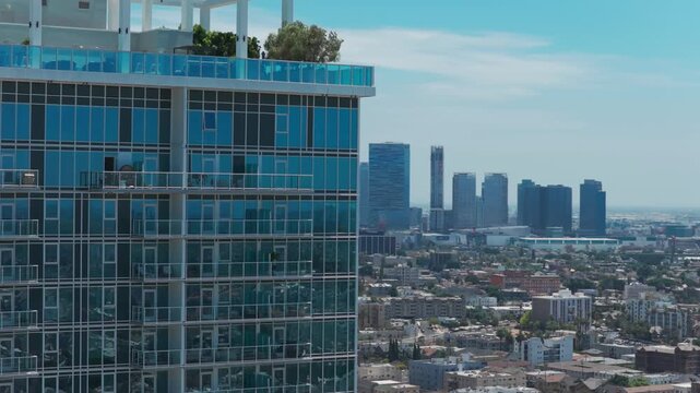 Telephoto shot revealing downtown Los Angeles behind a glass skyscraper in Southern California. 4K