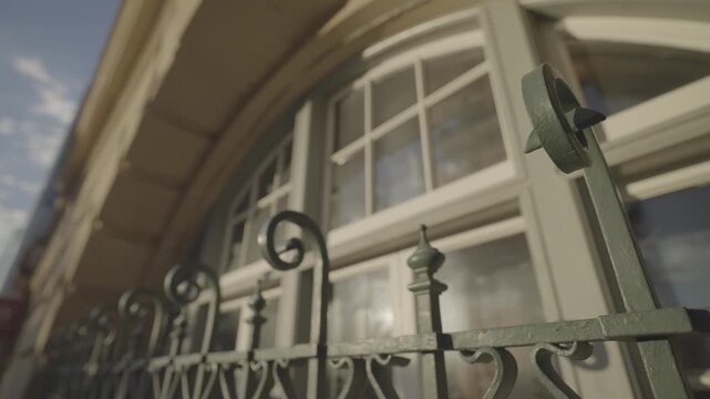 A close up view shows an arched window and ornate iron balustrade on a heritage building verandah.