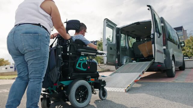 Personal assistant guiding a man with disability up a wheelchair ramp into an adapted van, accessible transportation.