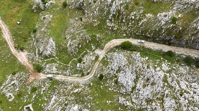 Aerial view of two off-road vehicles driving on a bumpy mountain trail in the south of Montenegro