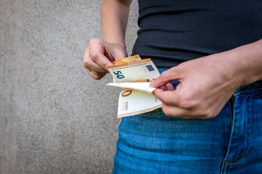 Person Counting Euro Banknotes Beside a Blue Jeans Pocket