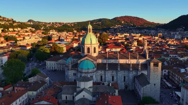 Como historic town on lake Como in Italy, orbiting drone shot of Como cathedral at sunset in golden light, tourism in Italian lake Como