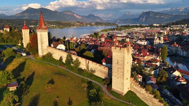 Lucerne medieval walls drone view at sunset, historic city of Lucerne in Switzerland, flying above Luzern, establishing shot of Lucerne downtown and Lucerne lake, tourism and travel in Switzerland
