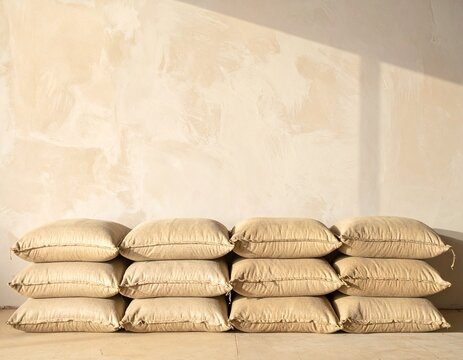Row of plain sandbags stacked as a low flood barrier against a warm wall