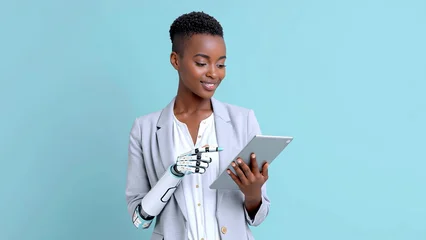Confident businesswoman with cybernetic hand holding tablet on light blue background © dashtik