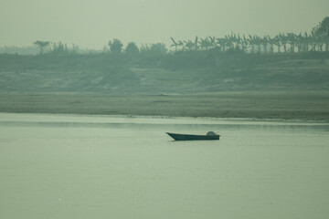 Small wooden fishing boat floating on calm river landscape scenery. © mssozib