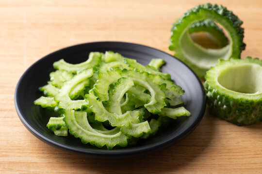 Sliced fresh bitter gourd or bitter melon on a black plate prepare for cook, Asian vegetables and herbal medicine
