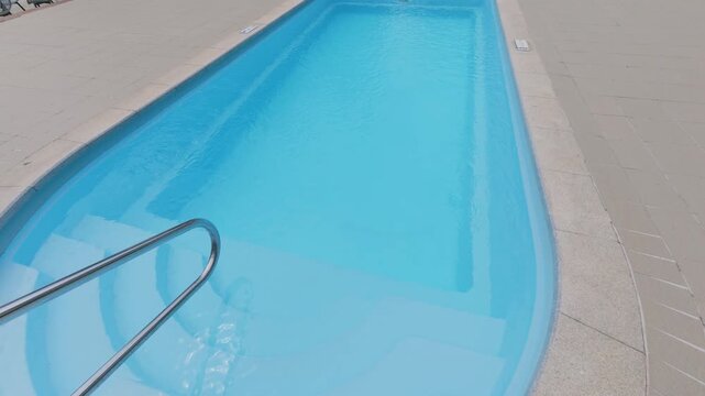 Clear Blue Swimming Pool Entry Steps with Metal Handrail at Resort