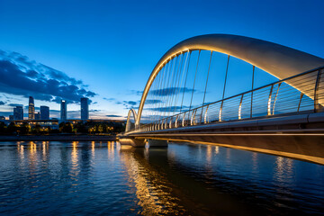 Naklejka premium Modern Pedestrian Bridge Over Urban River at Blue Hour