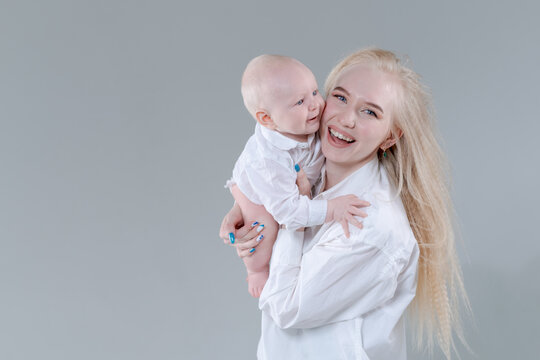 Laughing young caucasian mother and her cheerful baby boy cheek to cheek in a studio, ideal for happy family, love and parenting content