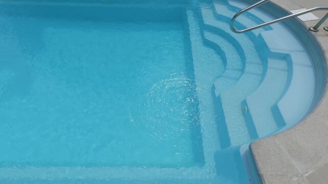 Clear Blue Swimming Pool Entry Steps with Metal Handrail at Resort