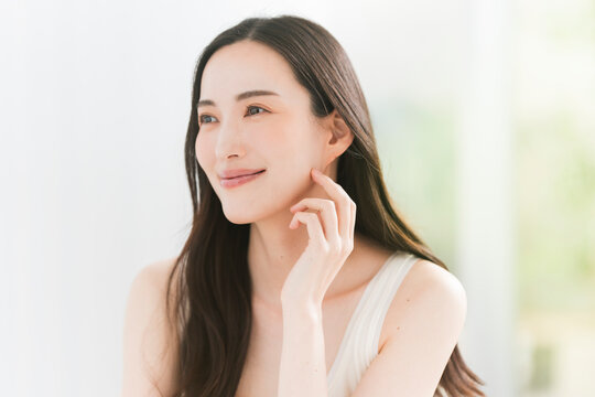 美しい肌と黒髪ロングヘアの笑顔の日本人女性。スキンケア・ヘアケアイメージ。