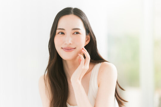 美しい肌と黒髪ロングヘアの笑顔の日本人女性。スキンケア・ヘアケアイメージ。