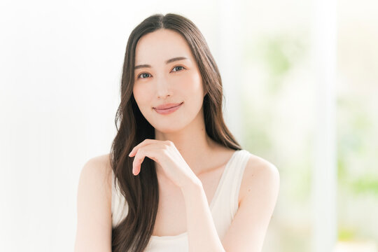 美しい肌と黒髪ロングヘアの笑顔の日本人女性。スキンケア・ヘアケアイメージ。