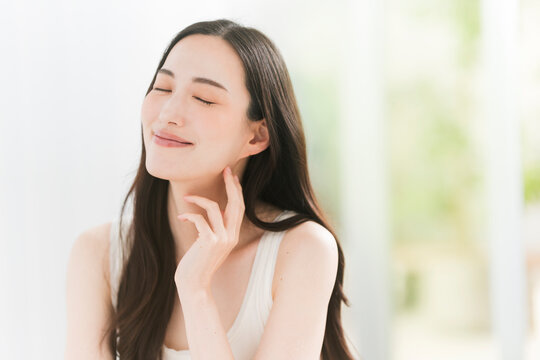 美しい肌と黒髪ロングヘアの笑顔の日本人女性。スキンケア・ヘアケアイメージ。