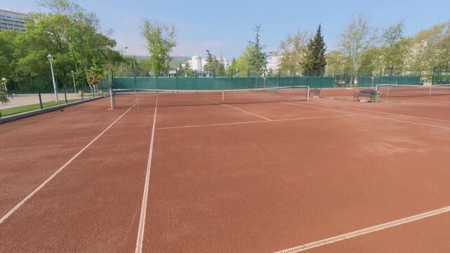 Outdoor Red Clay Tennis Court Pan Shot with Net and Lines on Sunny Day