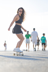 Skater rides on a sunny day while people walk along the pathway © KONSTANTIN SHISHKIN