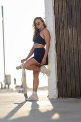 Skater poses by a wall near the beach on a sunny day © KONSTANTIN SHISHKIN