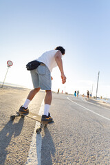 Skateboard rider showcases skills on a sunny day near the beach with people enjoying the outdoors © KONSTANTIN SHISHKIN