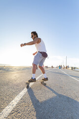 Skater rides along a pathway during sunset near a beach area with people in the background © KONSTANTIN SHISHKIN
