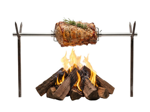 A seasoned roast spins over a campfire on a rotisserie, with flames visible.