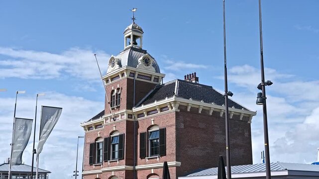 Harlingen, Netherlands. July 28, 2026. View of the historic town hall building with a clock tower and cupola under a bright blue sky with clouds.