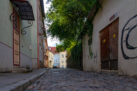 A low-angle view of the historic cobblestone Munga street in the old town of Tallinn, Estonia, featuring cozy medieval alleyways, ancient walls, and traditional architecture.