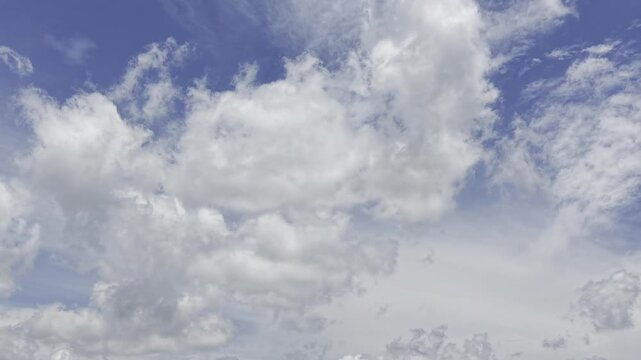 Puffy cumulus clouds drifting across bright blue daytime sky, full-frame cloudscape background