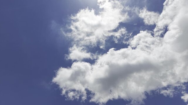 White fluffy clouds passing through deep blue daytime sky, tranquil weather background