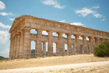Fototapeta premium Panoramic side perspective of the ancient Greek Doric temple under a blue sky in Segesta, Sicily, Italy