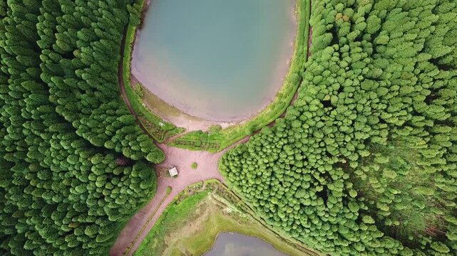 Bird's-eye descent across the twin Empadadas lakes and their forested causeway, Sao Miguel, Azores, Portugal