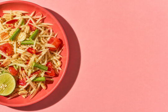 Overhead som tam salad on a modern coral background