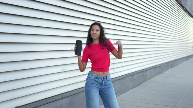 A Joyful Young Woman Happily Enjoying Her Favorite Music Outdoors with a Bluetooth Speaker