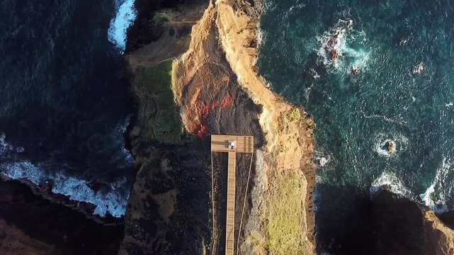 Descending drone over boardwalk to Farolim dos Fenais da Ajuda lighthouse, title sequence opener, Sao Miguel, Azores